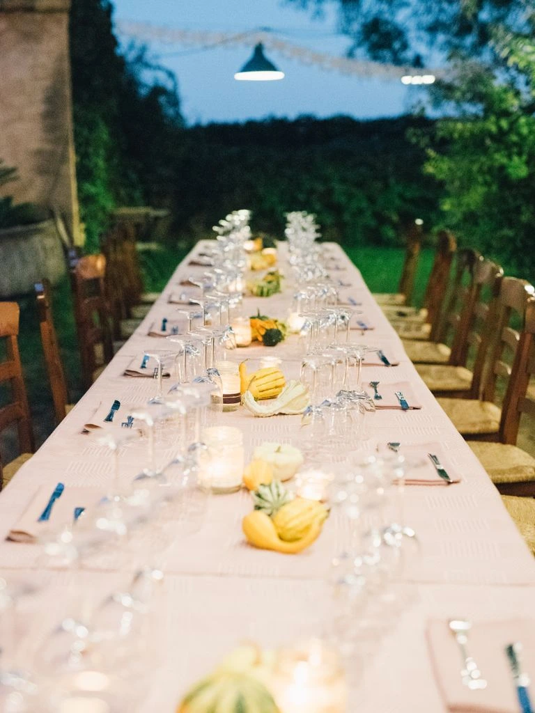 A long farm-table dinner under string lights at dusk.